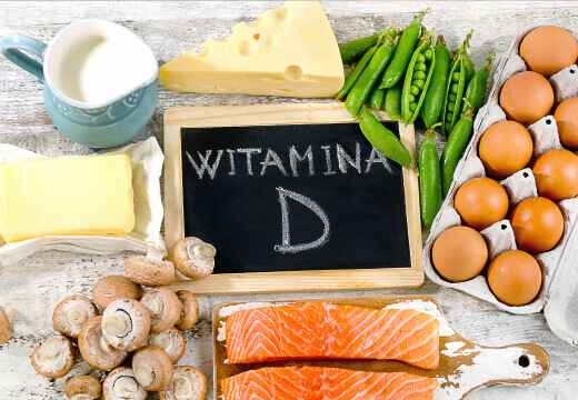 Natural Pharmaceuticals VitaSolaris® D3 Naturalne źródła witaminy D: mleko, ser, jaja, masło, pieczarki, groszek i filet z łososia na drewnianym tle.